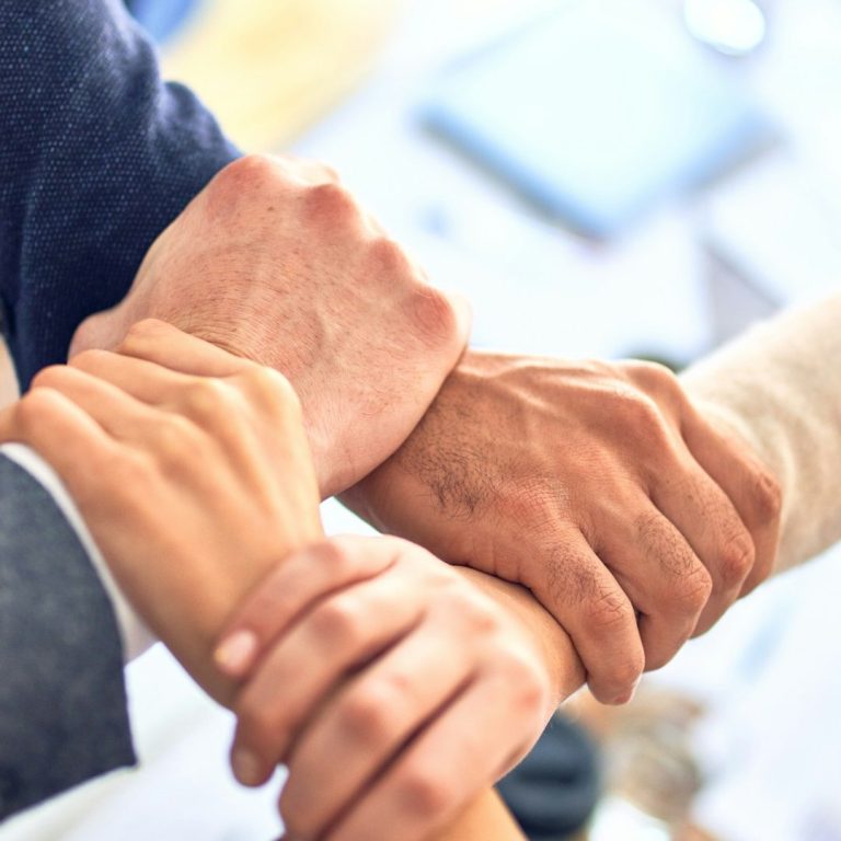 A group of hands clasped together, symbolising teamwork and solidarity.